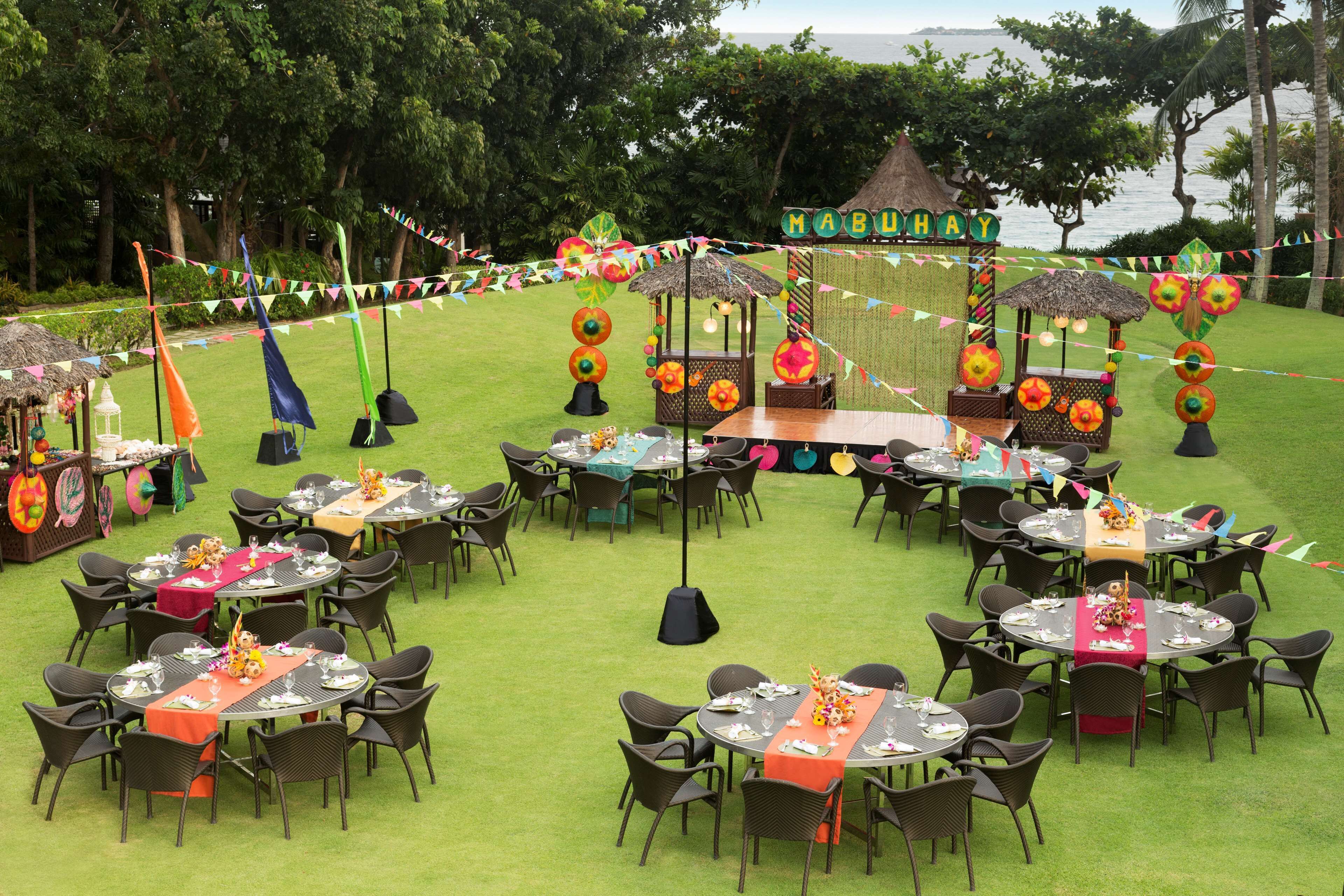 An outdoor dining area with round tables and chairs, decorated with colorful tablecloths and tropical-themed centerpieces.