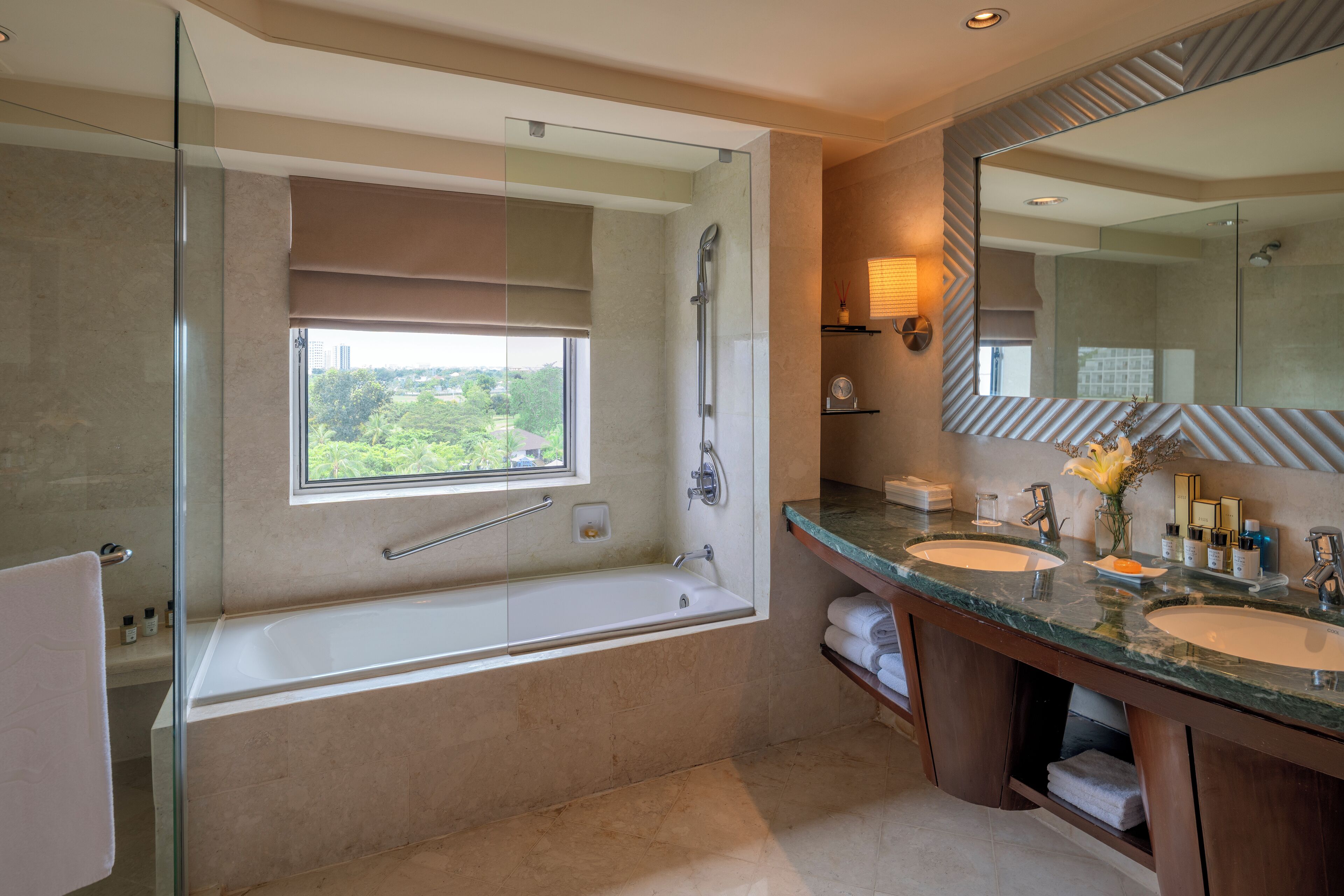 A modern bathroom with a glass-enclosed shower, a large bathtub, two sinks, and a large mirror.