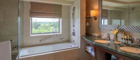 A modern bathroom with a glass-enclosed shower, a large bathtub, two sinks, and a large mirror.