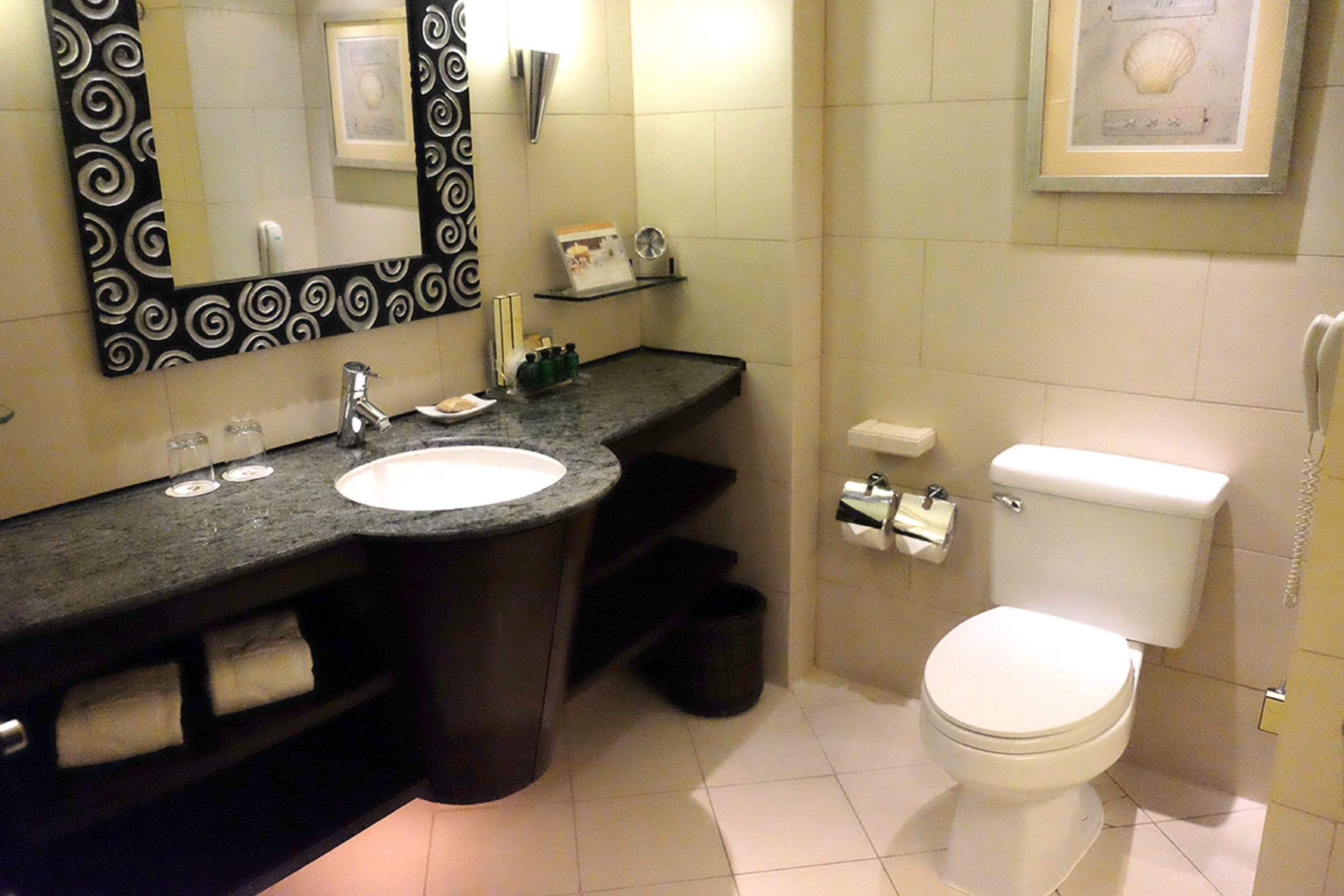 Une salle de bain avec un lavabo, un miroir, des toilettes et un tableau encadré au mur.