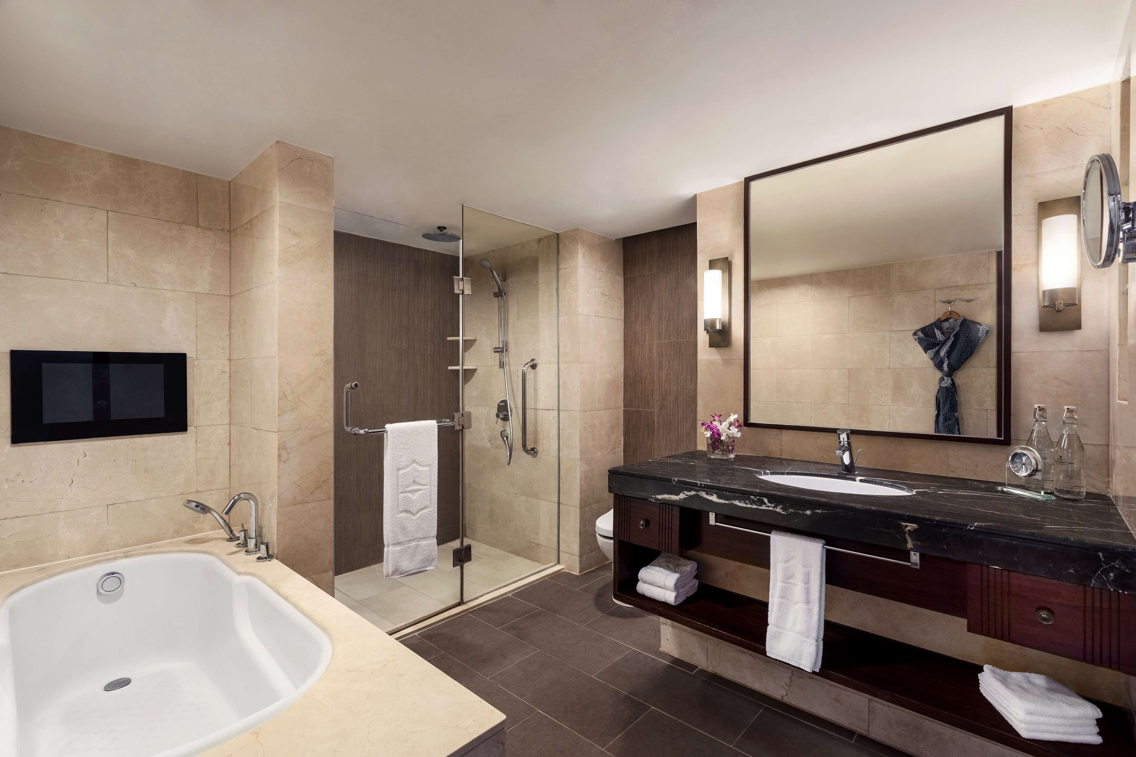 A modern bathroom with a large bathtub, a walk-in shower, a double sink vanity, and a large mirror.