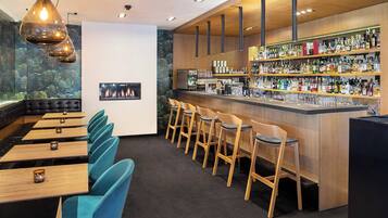 A bar area with multiple seating options, including bar stools and tables, and a variety of liquor bottles on shelves.