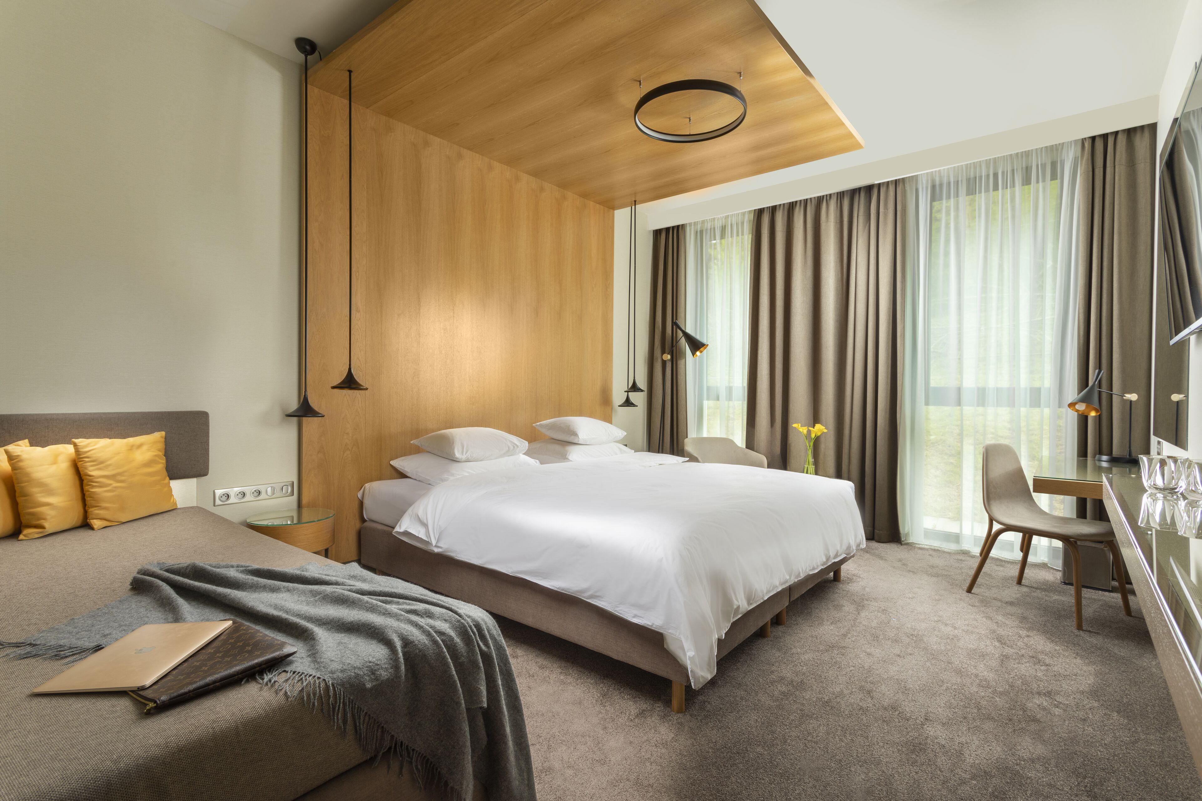 Una habitación de hotel moderna con una cama grande, un escritorio y vistas al exterior.