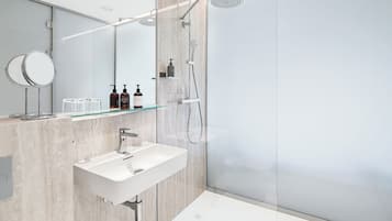 A modern bathroom with a glass shower enclosure, a white sink, and a mirror.