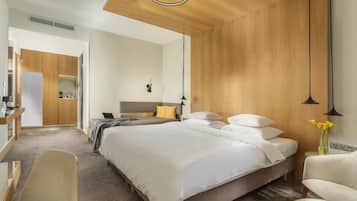Una habitación de hotel moderna con una cama grande, un escritorio, una silla y un armario.
