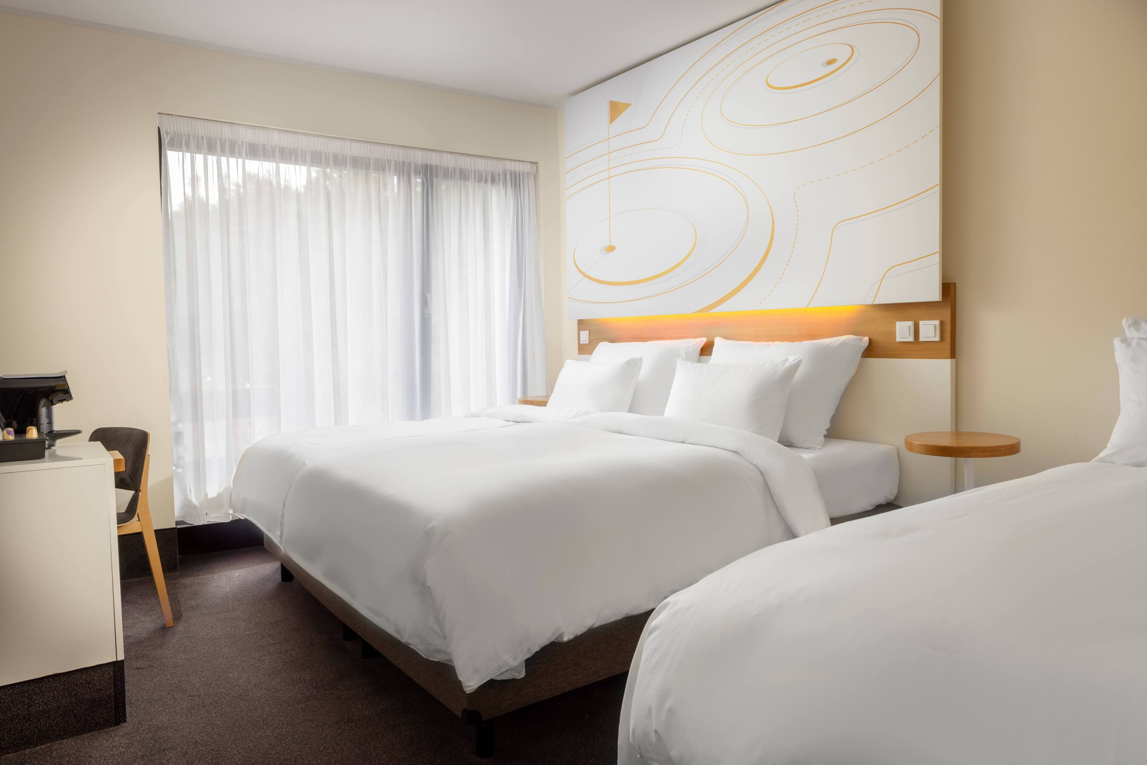 Habitación de hotel con una cama, un escritorio y una silla.