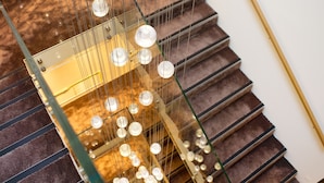 Een trap met een glazen balustrade en hangende bolvormige lampen.