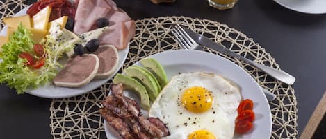 Un plato de desayuno con huevos, tocino, aguacate y diferentes quesos.