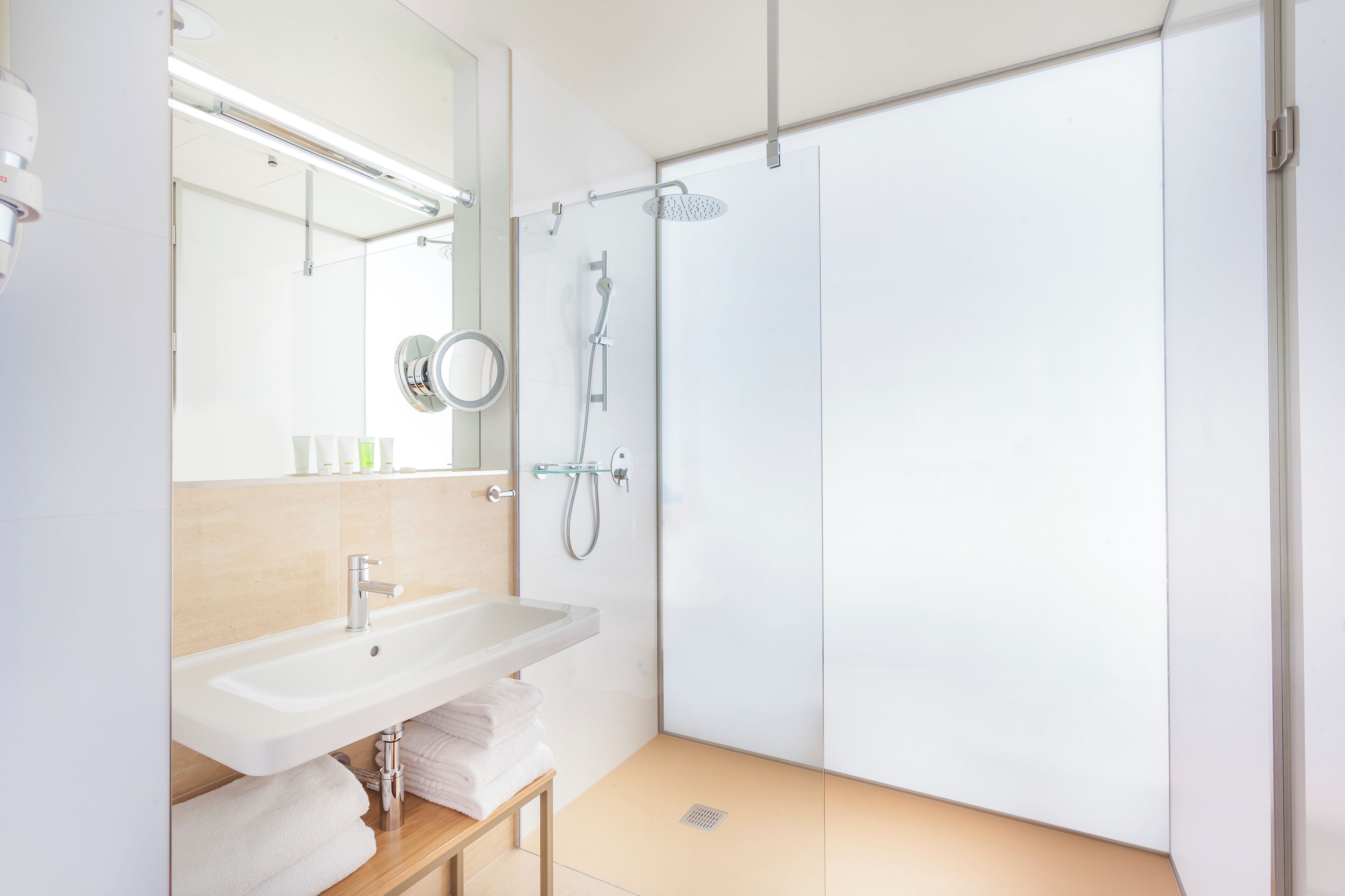 A modern bathroom with a sink, mirror, and shower.