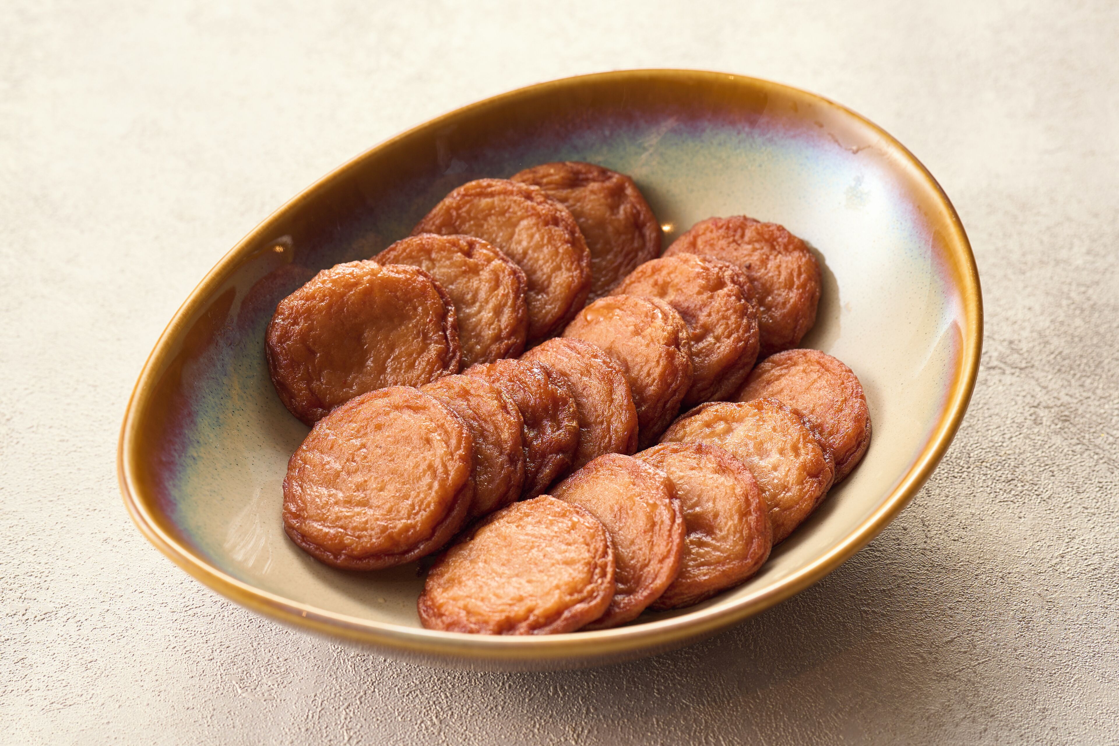 A bowl of sliced pastries on a textured surface.