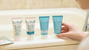 A bathroom with four Lamer by Thal Goja Pon hair and body care products on a shelf.