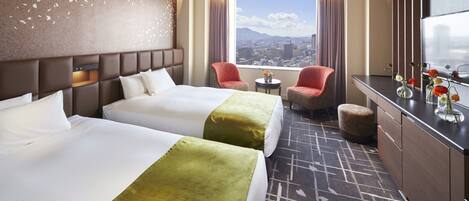 Une chambre d’hôtel avec deux lits, une vue sur la ville, une petite table et un coin salon avec des chaises.