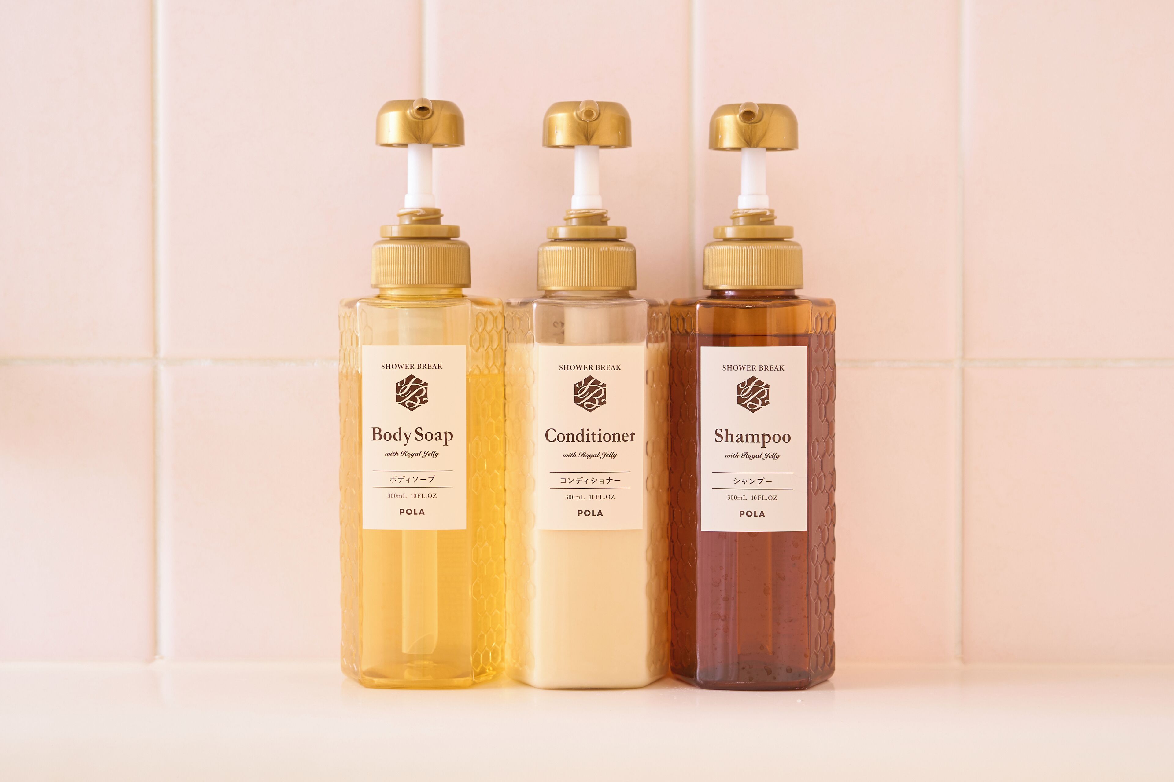 Tres botellas de productos para la ducha con dispensadores, cada una con el nombre de la marca y el tipo de producto.