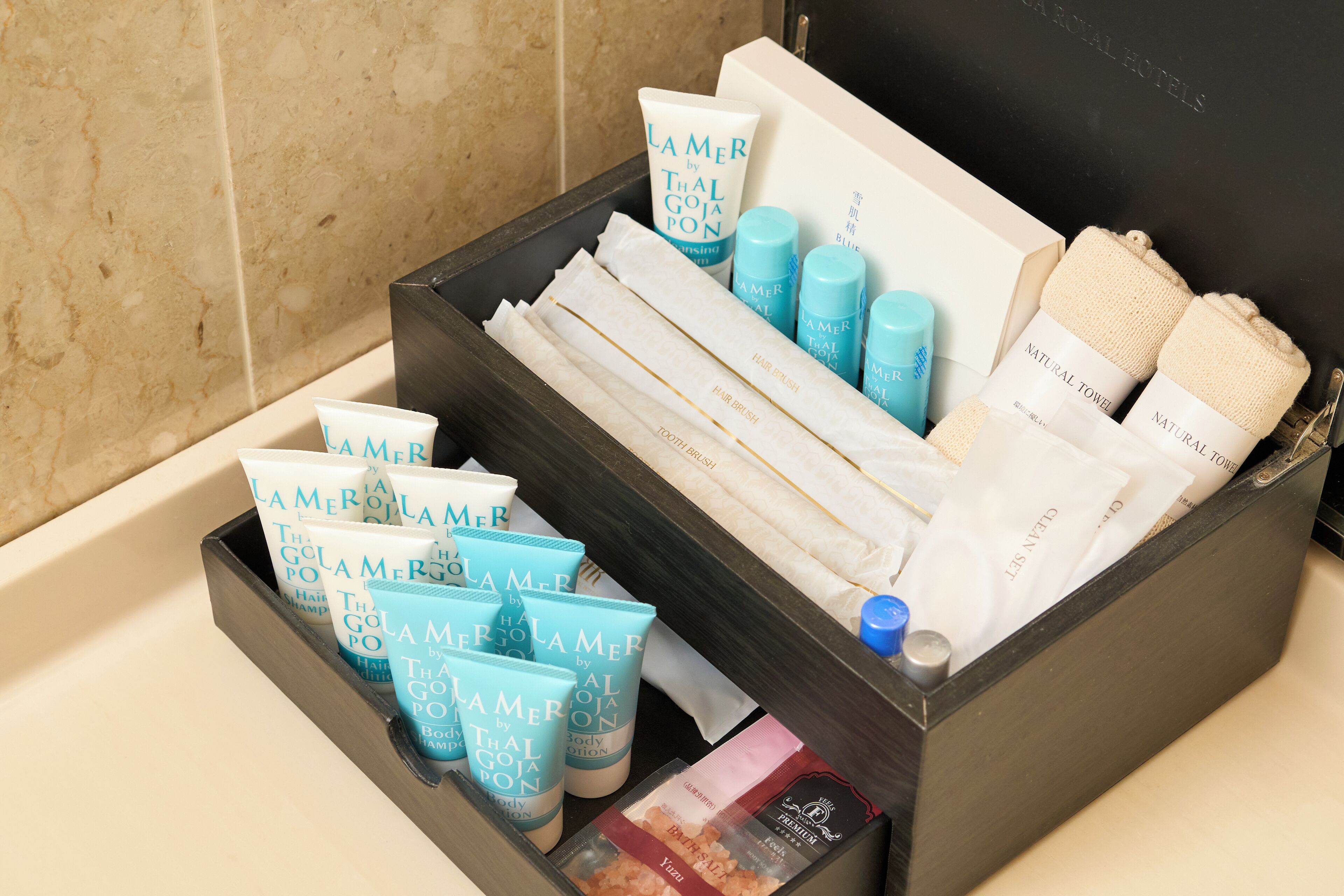 Un baño con un almacenamiento negro que contiene artículos de aseo como champú, acondicionador y gel de baño.