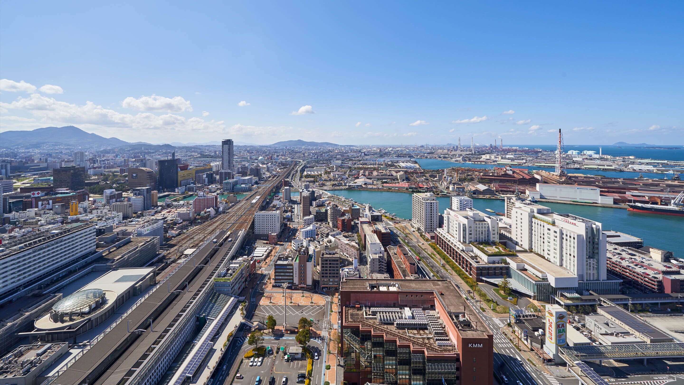 A cityscape with a prominent train station, a marina, and a mix of modern and traditional buildings.