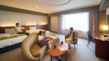 A hotel room with a bed, a sofa, a desk, and a window with curtains.