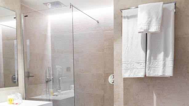 Een moderne badkamer met een douche met glazen wand, een wit wastafelmeubel en een toilet.