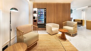 A modern lounge area with seating, a coffee machine, and a vending machine.