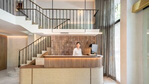 A reception area with a modern design, featuring a reception desk, a staircase, and a large window with curtains.