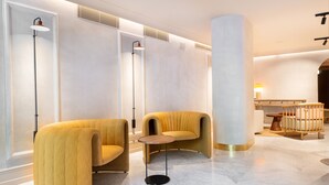 A modern lobby with two yellow armchairs, a round table, and a large pillar.