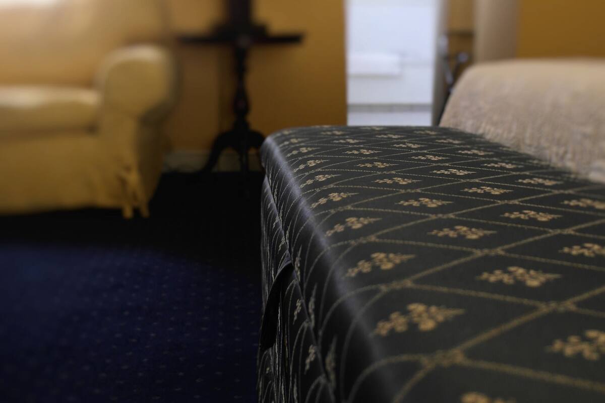 Ein Hotelzimmer mit Bett, Sessel und Lampe.
