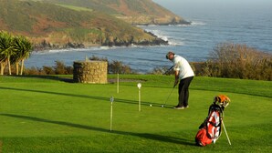 Ein Golfplatz mit Blick auf das Meer und die Hügel.