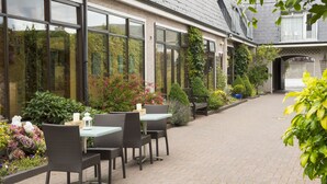 Eine Terrasse im Freien mit Korbmöbeln und Kübelpflanzen.