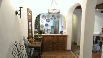A narrow hallway with a wooden counter, a mirror, and a decorative metal railing.