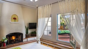 Ein Schlafzimmer mit Kamin, Bett, Fernseher und einem Fenster mit Vorhängen.