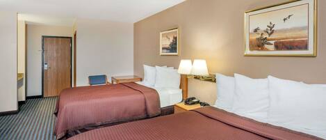 Ett hotellrum med två sängar, ett skrivbord, en stol och en tavla på väggen.