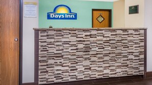 Ein Empfangstresen mit Days Inn Logo, einer Holztür und einem an der Wand befestigten Schild.