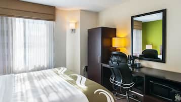 A hotel room with a bed, a desk, a chair, a television, and a mirror.