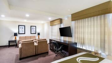 A hotel room with a bed, a desk, a chair, a sofa, and a TV.