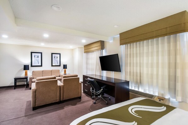 Una habitación de hotel con una cama, un escritorio, una silla, un sofá y un televisor.