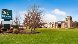 A Quality Inn hotel with a sign, a lawn, and a building with a clock tower.