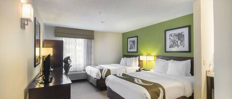 Habitación de hotel con dos camas, un escritorio, una computadora y una ventana con cortinas.
