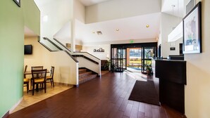 A spacious lobby with a staircase, a reception desk, and a dining area.