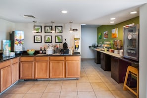 A modern kitchen with a central island, various appliances, and a green accent wall.