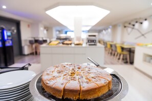 Un pastel redondo sobre un plato de servir en una cocina moderna con una lámpara de techo brillante.