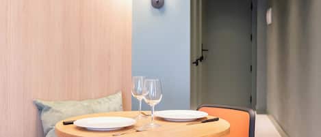 Uma sala de jantar com uma mesa redonda, duas taças de vinho e pratos.