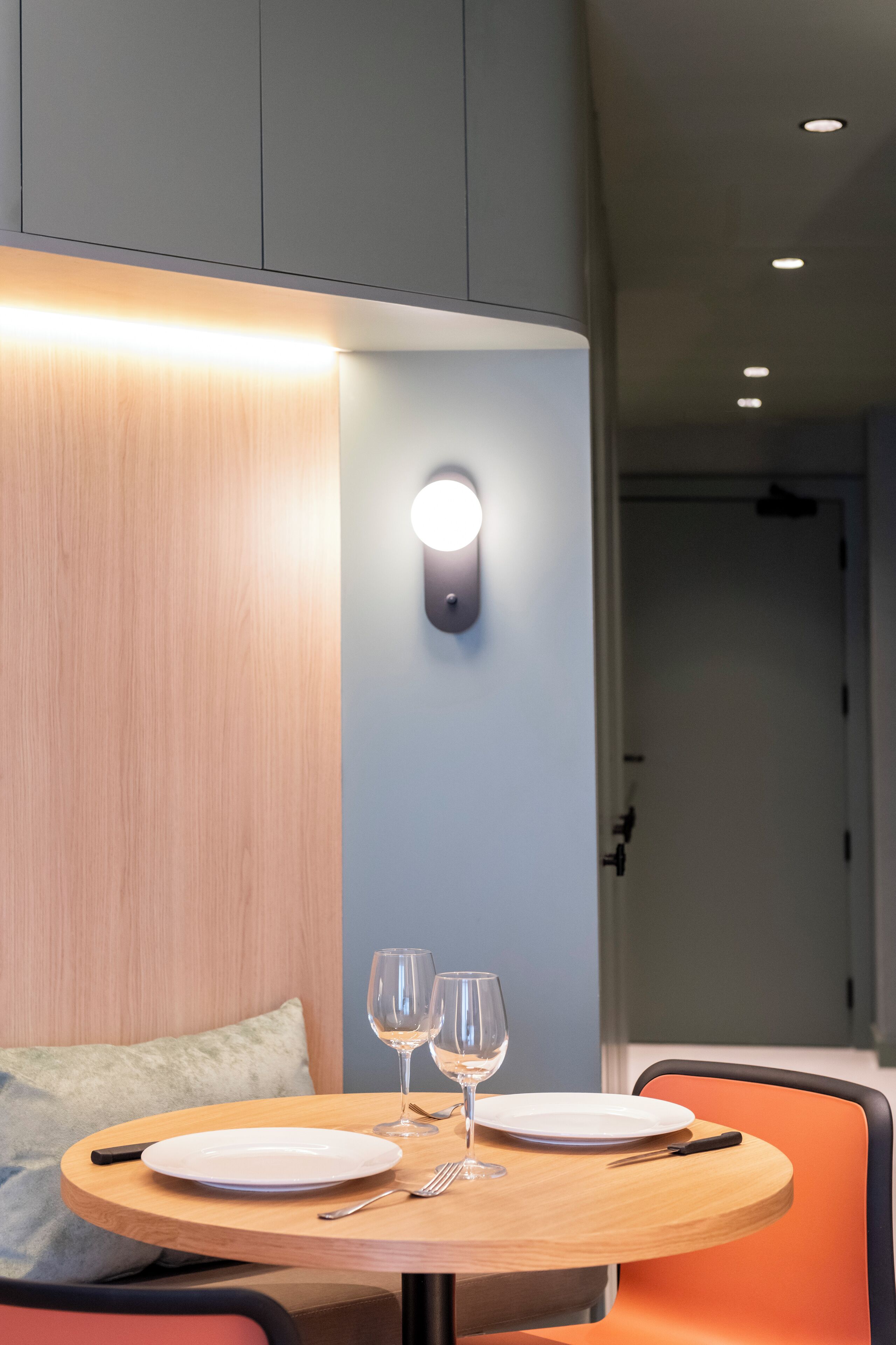 A dining area with a round table, two wine glasses, and a plate.