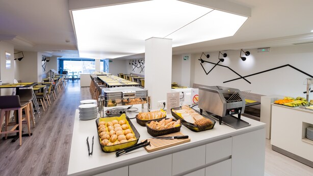 Una cafetería moderna con una barra larga, diferentes opciones de comida y una estación de parrilla.