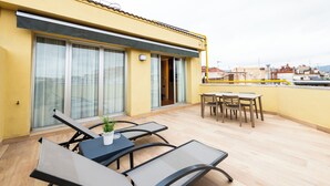 Un edificio amarillo con balcón, amplias puertas correderas de vidrio y una mesa con sillas.