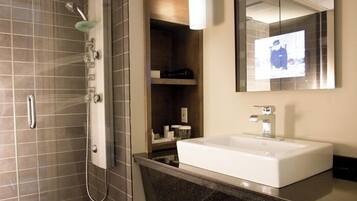 Un baño moderno con ducha, un espejo grande y un lavamanos blanco.