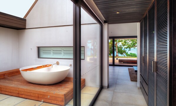 A modern bathroom with a large bathtub, a window, and a view of the outdoors. - Vomo Island Resort (Vomo Island)