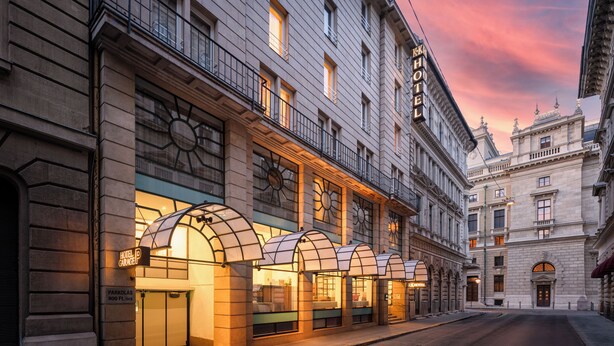 Un hotel con fachada clásica, varios balcones y un cartel llamativo.