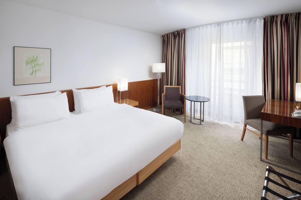 Une chambre d’hôtel avec un grand lit, un bureau, une chaise et une lampe.