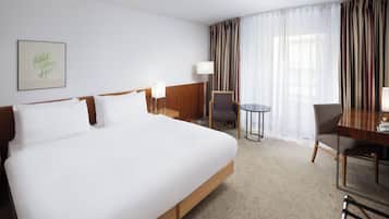 Une chambre d’hôtel avec un grand lit, un bureau, une chaise et une lampe.