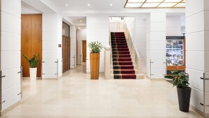 Vestíbulo de hotel con una escalera, una recepción y una minibar.