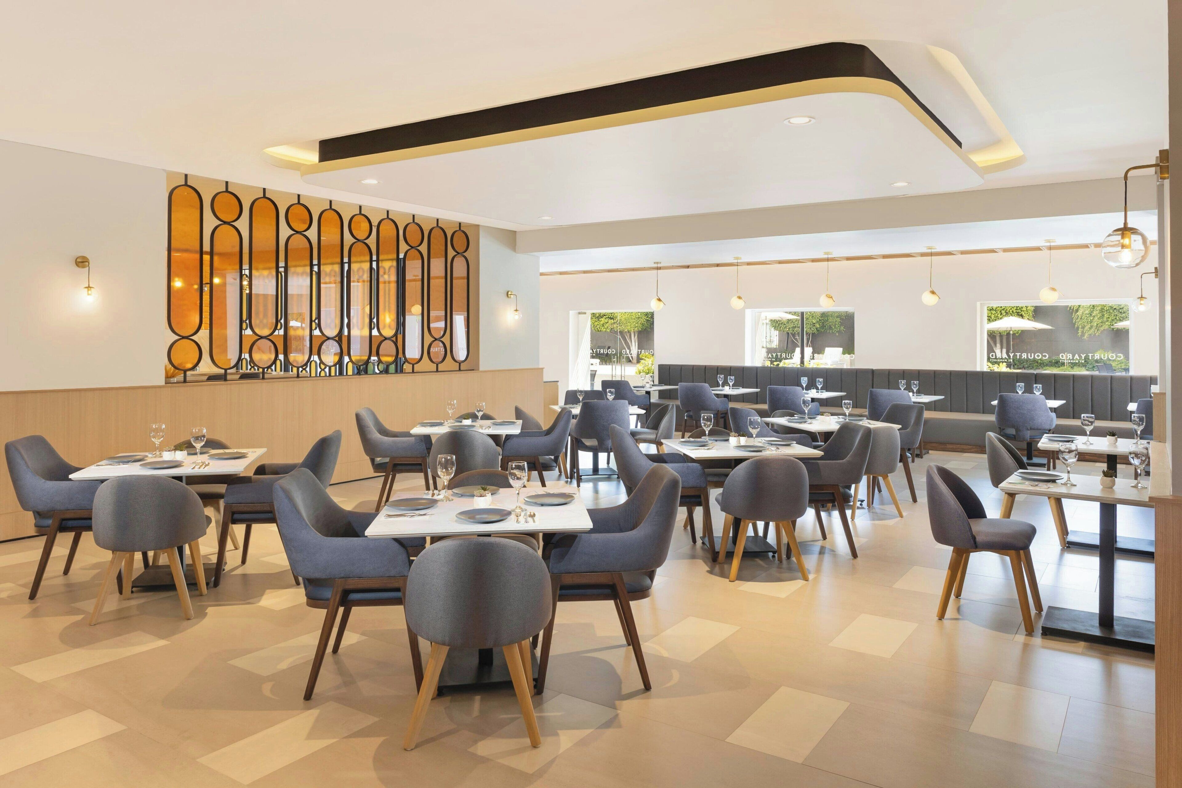 A modern restaurant with a clean, geometric floor plan, contemporary furniture, and a decorative wall feature.